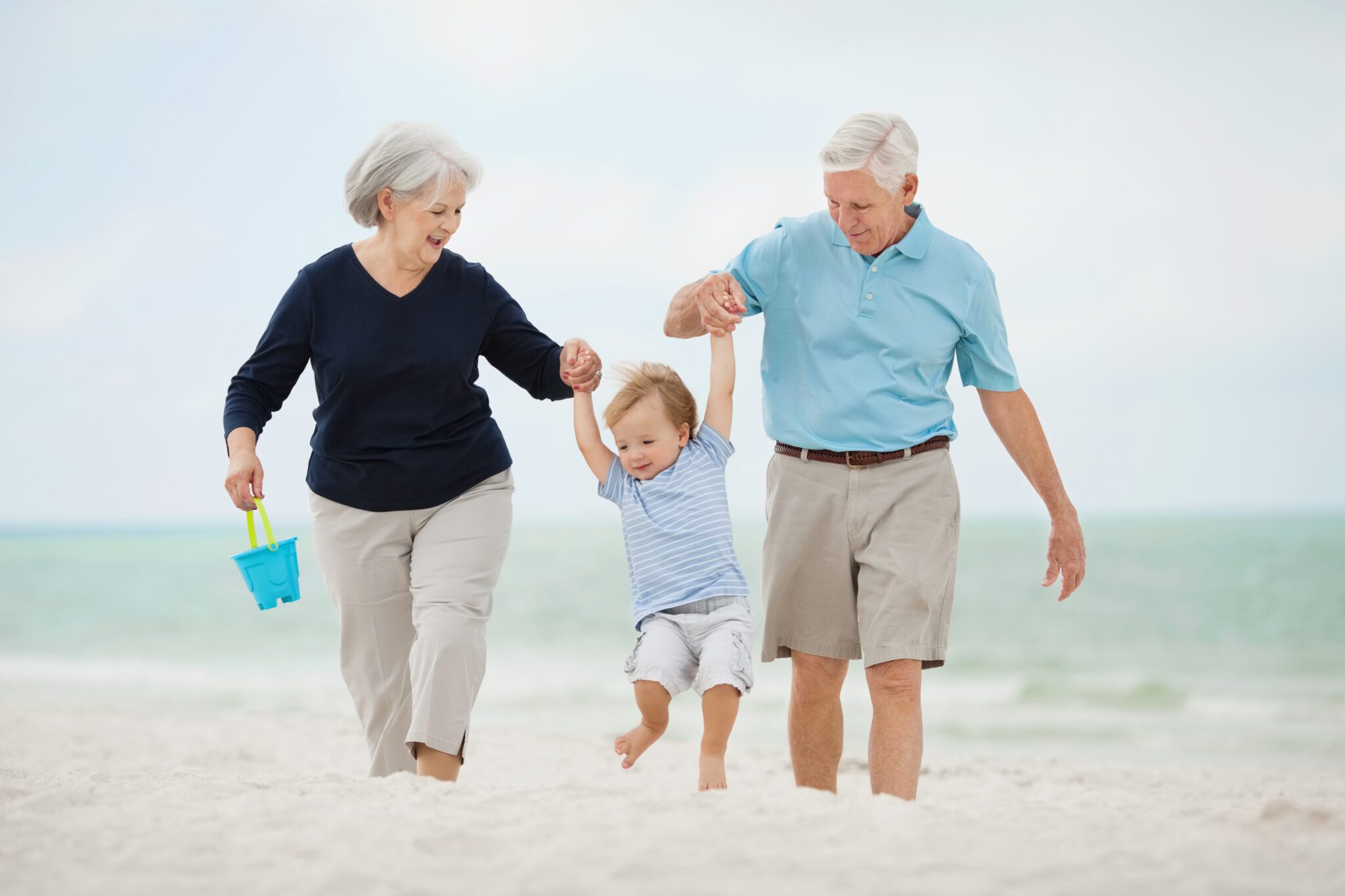 Besteforeldre som koser seg på stranda med barnebarn.